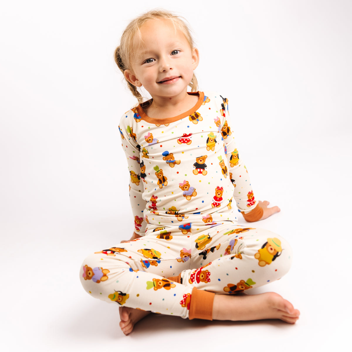 Smiling girl sitting cross-legged in Main Street Bears long sleeve bamboo pajamas