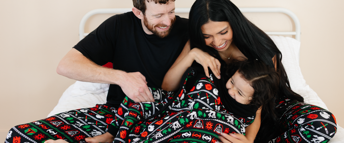 Family snuggling in matching Merry Galaxy bamboo pajamas from Bam & Stitch