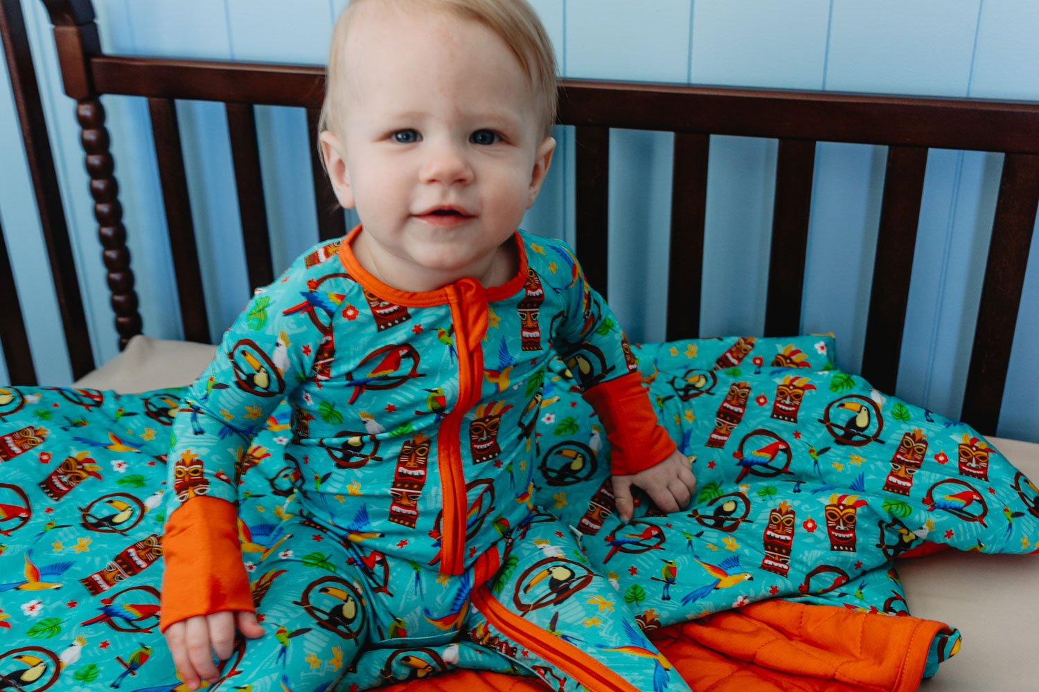a toddler in the crib wearing the tiki party convertible romper
